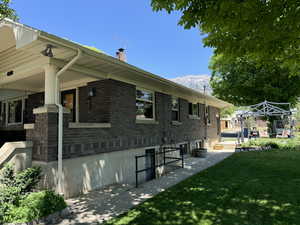 View of home's exterior featuring a chimney, a lawn, brick siding, and a mountain view