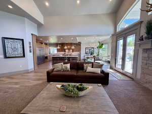 Living area with a towering ceiling, plenty of natural light, recessed lighting, a chandelier, and light tile wood finished floors