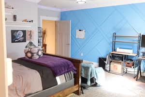 basement Bedroom 1-with a decorative wall, carpet floors, and crown molding