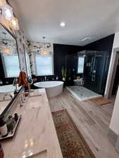 Full bathroom with a textured ceiling, a freestanding bath, a 2 shower heads, European style glass walls double vanity, and tile- wood finished floors