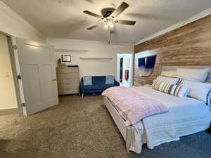 Basement bedroom 2-featuring a textured ceiling, wooden walls, a ceiling fan, and crown molding