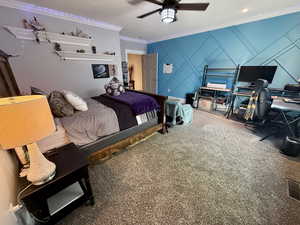 Basement bedrooms 1-Carpeted bedroom featuring ornamental molding, a decorative wall, ceiling fan, and a desk