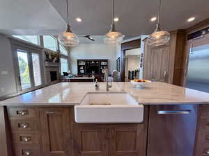 Kitchen with a sink, open floor plan, a fireplace, Walnut cabinets, and hanging light fixtures