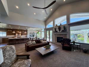 Living area featuring recessed lighting, high vaulted ceiling, a ceiling fan, tons of natural light, and gas fireplace with natural stone surround
