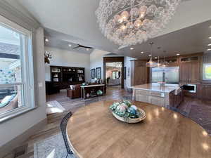 Dining space with wood finished floors, a chandelier, baseboards, chandelier, and vaulted cielings