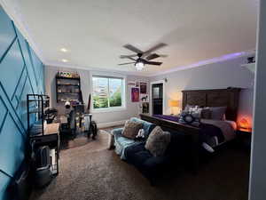 Basement bedroom 1-Carpeted bedroom with ornamental molding, a ceiling fan, and a textured ceiling