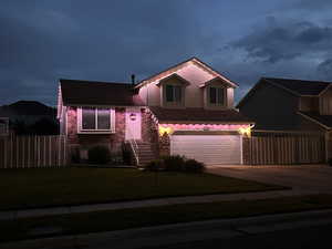 Tri-level home with stone siding, concrete driveway, an attached garage, and roof with shingles