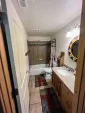 Full bath with toilet, vanity, shower / bath combo, tile patterned flooring, and a textured ceiling