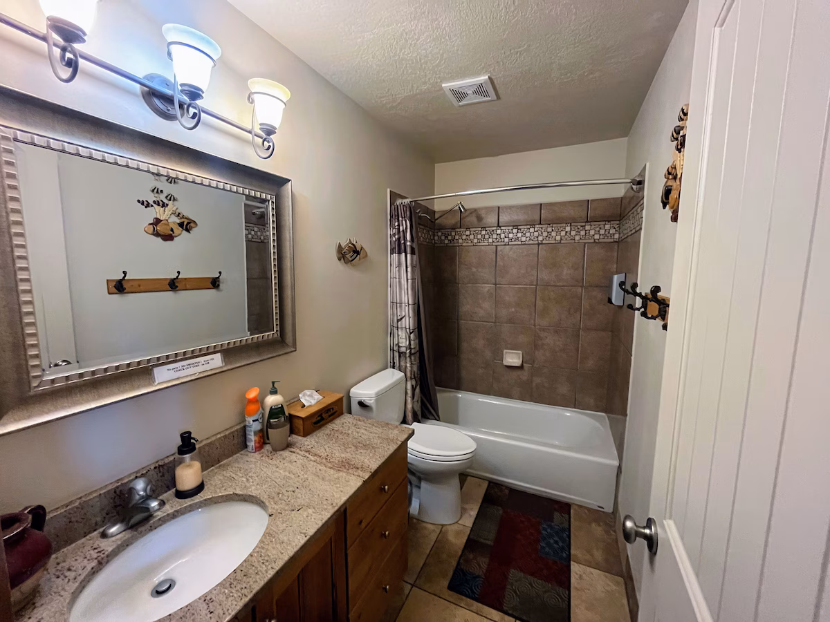 Full bath with toilet, vanity, shower / bath combo, a textured ceiling, and tile patterned floors