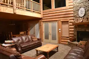Living area with rustic walls, a towering ceiling, french doors, a stone fireplace, and carpet flooring