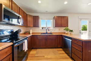 Kitchen with stainless steel appliances, a sink, light wood-style floors, a peninsula, and recessed lighting