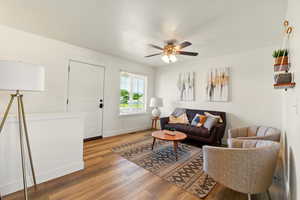 Living area featuring light wood finished floors, a ceiling fan, and baseboards