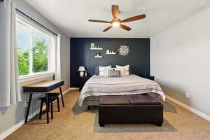 Bedroom featuring light colored carpet, ceiling fan, and baseboards