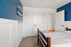 Carpeted bedroom with a closet and wainscoting