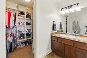 Bathroom featuring vanity, a spacious closet, and baseboards