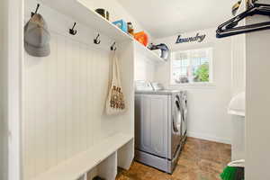 Laundry room featuring washer and dryer, stone finish flooring, and baseboards