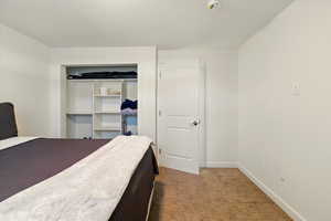 Bedroom with dark colored carpet, baseboards, and a closet