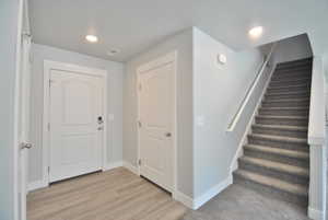 Entrance foyer featuring baseboards, stairway, and light wood finished floors