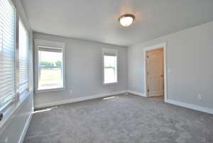 Main bedroom featuring carpet floors and baseboards, smart plugin for fast charging, and extra windows.