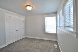 Bedroom with carpet flooring, baseboards, and a closet with ample window looking over the community.