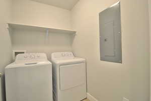 Laundry area with electric panel, independent washer and dryer, and baseboards
