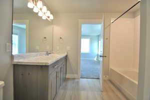 Full bathroom with vanity, wood finished floors, baseboards, and tub / shower combination