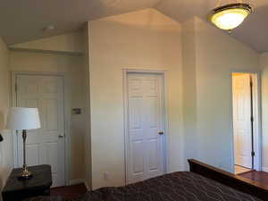Unfurnished bedroom with lofted ceiling and baseboards