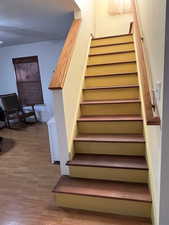 Staircase with wood finished floors and baseboards