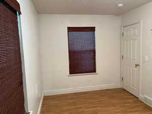 Unfurnished bedroom featuring light wood finished floors, baseboards, and a textured ceiling