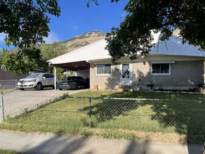 View of front of house with brick siding, a mountain view, driveway, and an attached carport