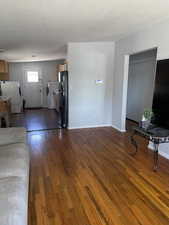 Unfurnished living room featuring dark wood finished floors and washing machine and clothes dryer