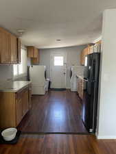 Kitchen featuring freestanding refrigerator, dark wood-style floors, light countertops, and brown cabinetry