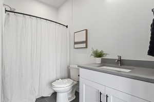 Bathroom featuring toilet, tile patterned flooring, vanity, and a shower with shower curtain