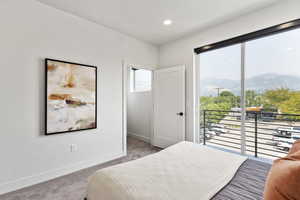 Model Home Bedroom featuring a mountain view, light colored carpet, access to outside, baseboards, and recessed lighting