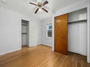Unfurnished bedroom featuring light wood finished floors, baseboards, a ceiling fan, and multiple closets