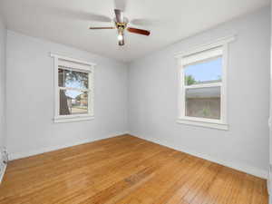 Spare room with healthy amount of natural light, light wood-style flooring, a ceiling fan, and baseboards