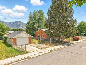 View of front facade with brick siding, a mountain view, a detached garage, and an outbuilding