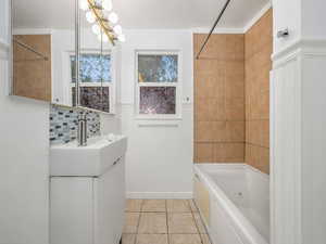 Full bathroom with  shower combination, vanity, tile patterned floors, wainscoting, and backsplash