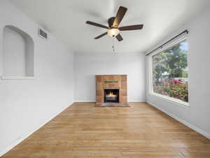 Unfurnished living room featuring ceiling fan, light wood-style floors, a fireplace, and baseboards