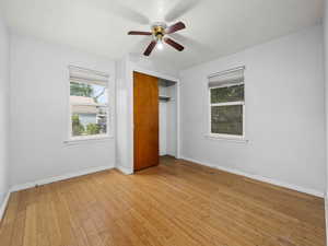 Unfurnished bedroom with a closet, baseboards, light wood-style flooring, and a ceiling fan