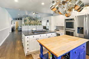 Kitchen with a center island, butcher block counters, appliances with stainless steel finishes, tasteful backsplash, and a ceiling fan