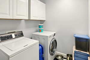 Washroom featuring separate washer and dryer, cabinet space, and baseboards