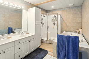 Bathroom featuring tile walls, a shower stall, a bath, tile patterned flooring, and double vanity