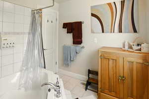 Bathroom with tile patterned flooring, shower / bathtub combination with curtain, baseboards, and vanity