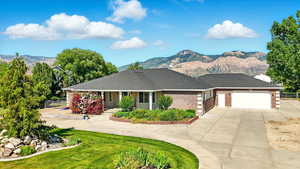 View of front facade featuring driveway, a mountain view, an attached garage, and brick siding