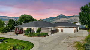 View of front facade featuring driveway, an attached garage, brick siding, and a mountain view