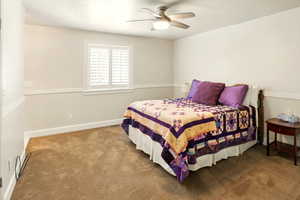 Carpeted bedroom with ceiling fan and baseboards