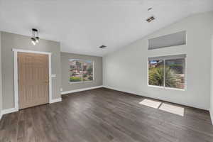 Entrance foyer with dark wood-style floors, vaulted ceiling, and baseboards