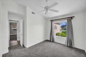 Spare room featuring carpet floors, vaulted ceiling, baseboards, and ceiling fan