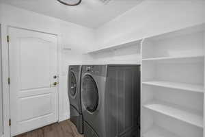 Laundry room featuring washing machine and clothes dryer and dark wood-type flooring